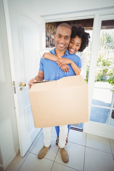 Homebuyers entering their new home with packing box